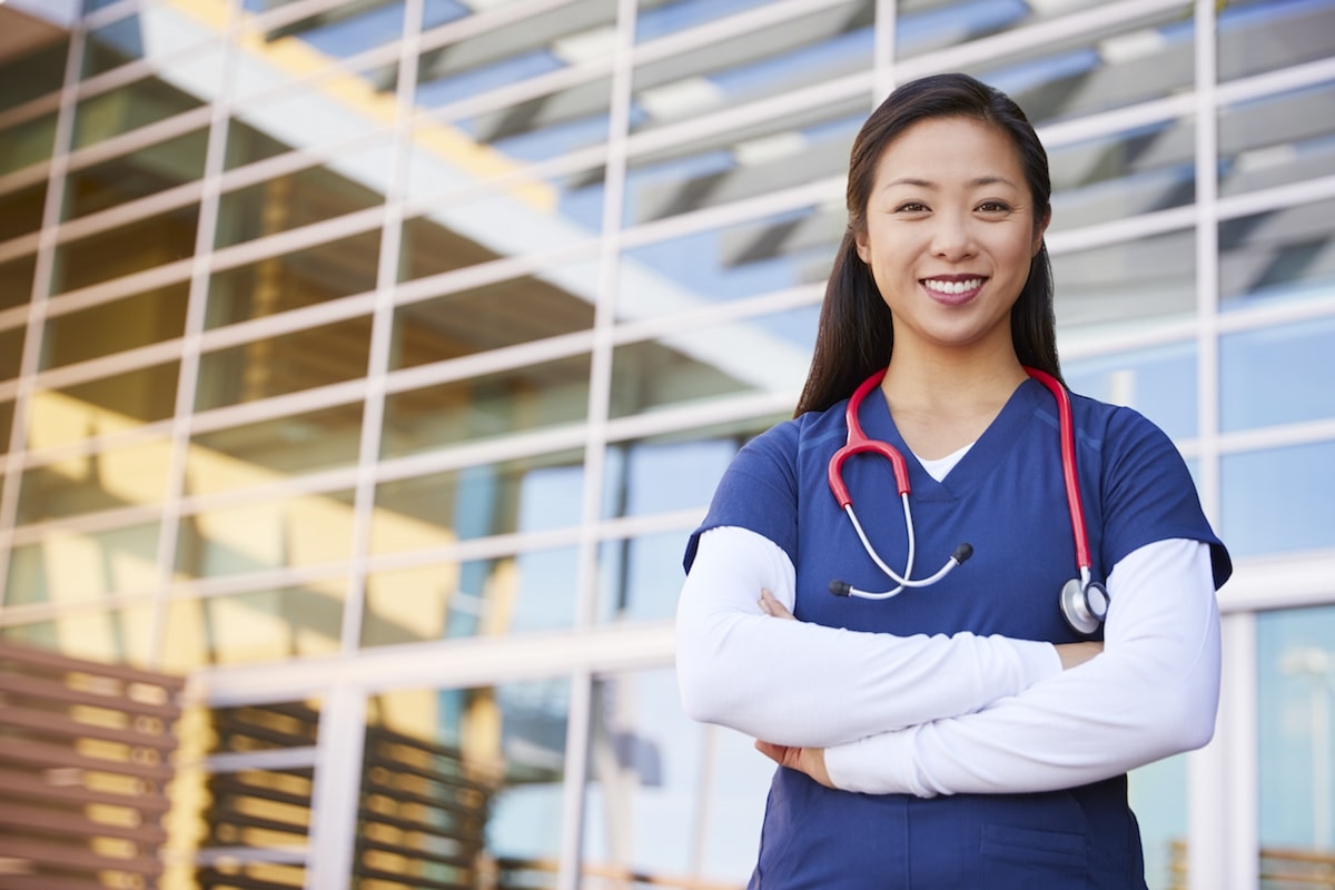 Physician fellow smiling while standing outside of hospital with arms crossed